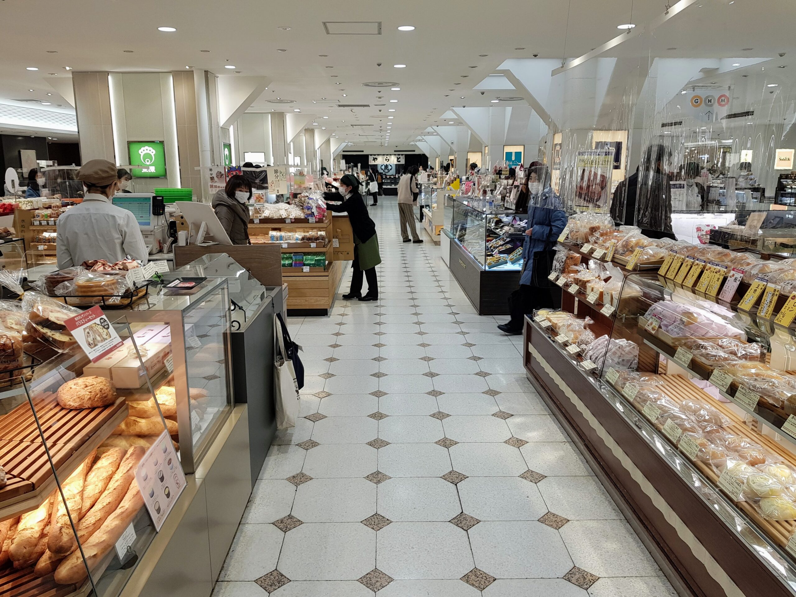Busy depachika food hall corridor with bakery, prepared food counters, and specialty stalls